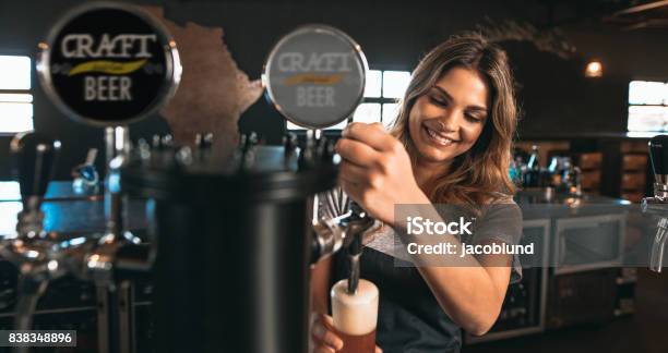 Female Bartender Tapping Craft Beer In Bar Stock Photo - Download Image Now - Bartender, Women, Beer Tap