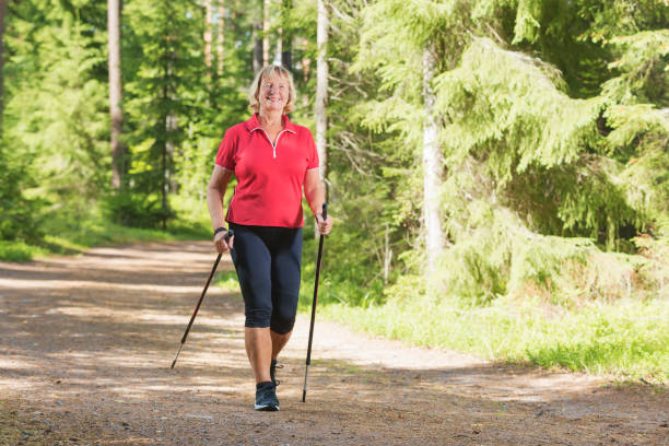 Active senior woman doing nordic walk exercise Nordic walking active senior woman working out in the forest and enjoying beautiful summer day. nordic walking pole stock pictures, royalty-free photos & images