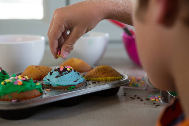 istock Cropped hand of boy decorating cupcakes with sprinklers 838371358