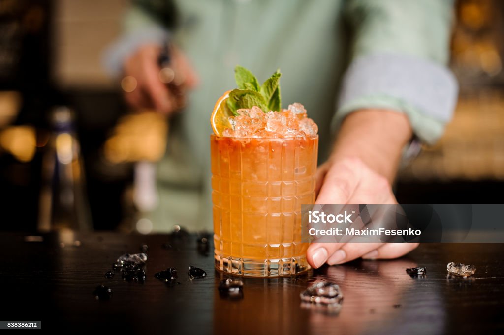 Bartender finished decorating his cocktail Bartender finished decorating his cocktail with mint and orange slice Cocktail Stock Photo
