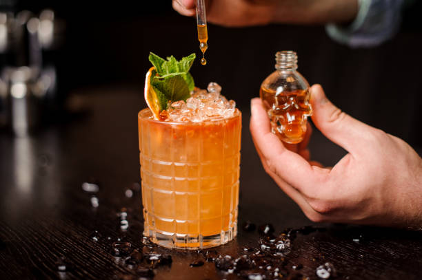 istock small skull-shaped bottle, orange cocktail and barmen hand 838386266