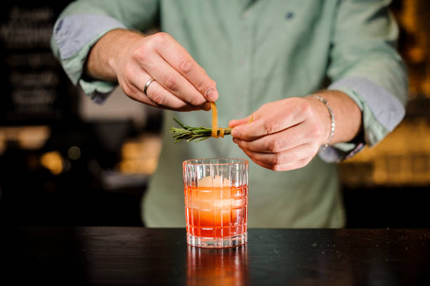 istock Bartender decorates cocktail with orange peel and rosemary close up 838386874