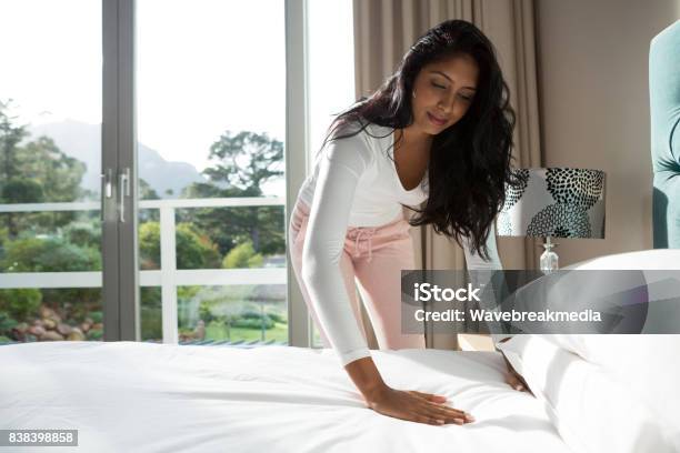 Young Woman Making Bed At Home Stock Photo - Download Image Now - Bed - Furniture, Making, Preparation