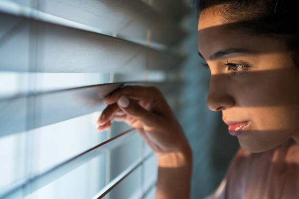 istock Thoughtful woman looking through window blinds 838398962