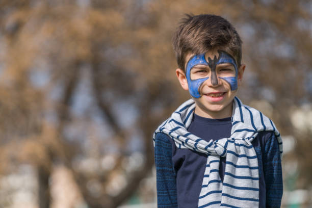 Children face painting. Boy  painted as tiger or ferocious lion by make up artist. Preparing for theatrical performance. Boy actor playing role. Tiger mask face