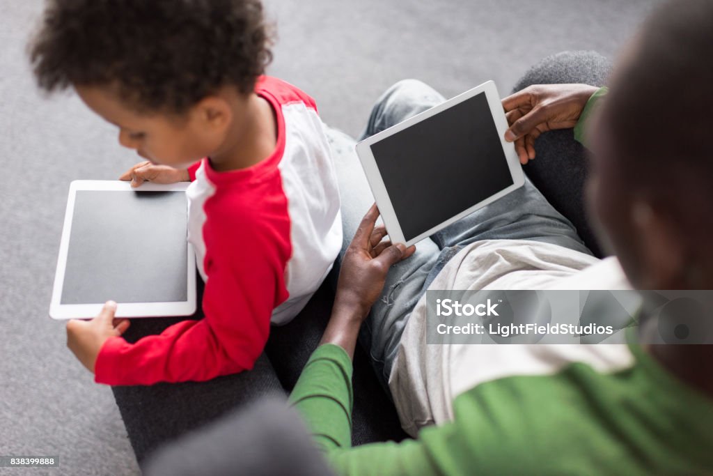 father and son using tablets top view of father and son using digital tablets African-American Ethnicity Stock Photo