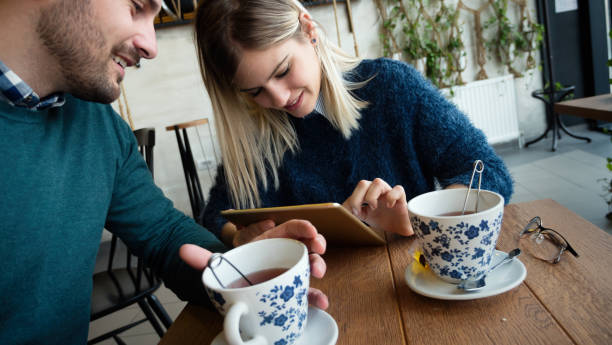 istock Young attractive man and beautiful woman on date looking on tablet 838402072
