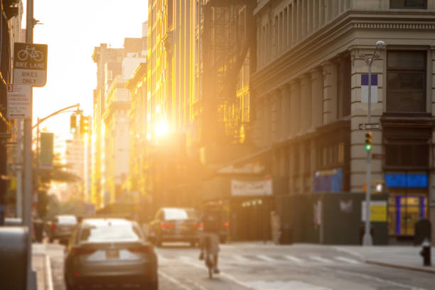 livreur de promenades en vélo dans les rues de new york city avec le soleil se reflétant sur le centre-ville de construction windows - brooklyn sign new york city queens photos et images de collection