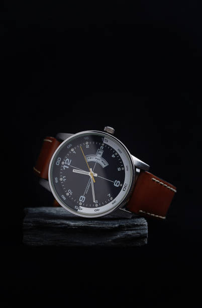 Wrist watch with a black dial on a gray stone with a dark background. Wrist watch with a black dial on a gray stone with a dark background. belt leather isolated close up stock pictures, royalty-free photos & images