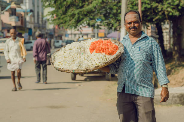 street life and man with huge tray of flowers for indian puja on - india bangalore flower business imagens e fotografias de stock