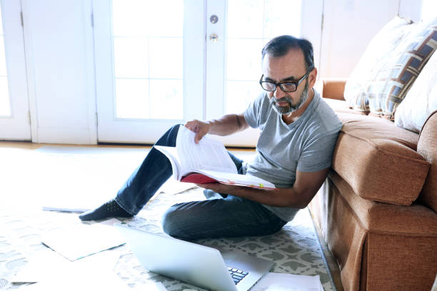 istock Latino Man Sits On Floor Leaning Against Couch While Working From Home 838425184