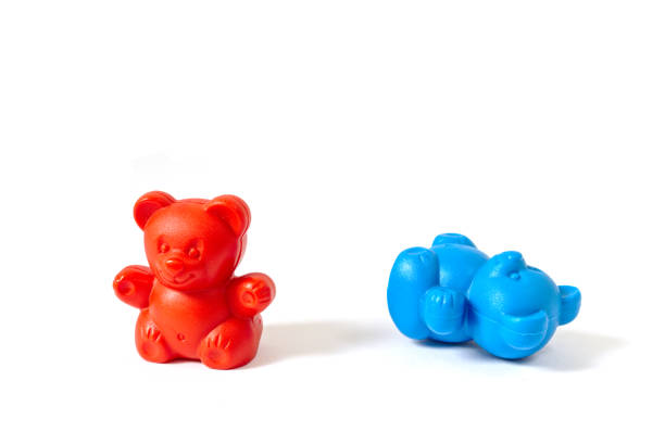 istock Red plastic toy bear standing with blue plastic toy bear knocked over 838432036