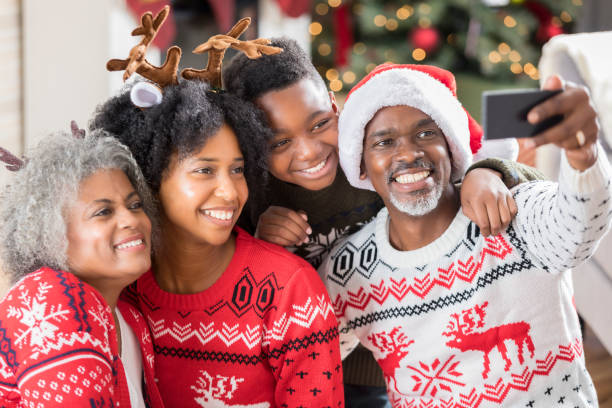 Multi-generational family takes selfie on Christmas morning Playful African American family take a selfie on Christmas morning while wearing Christmas sweaters. christmas sweater photos stock pictures, royalty-free photos & images