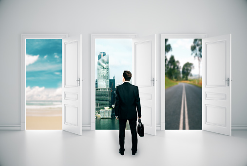 Back view of young businessman in concrete interior with three open doors and different views. Success concept. 3D Rendering