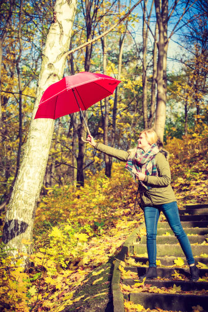 istock Woman walking in park with umbrella, strong wind 838442848