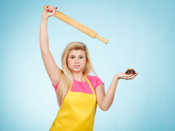 istock Woman holding cupcake and rolling pin wearing apron 838445668