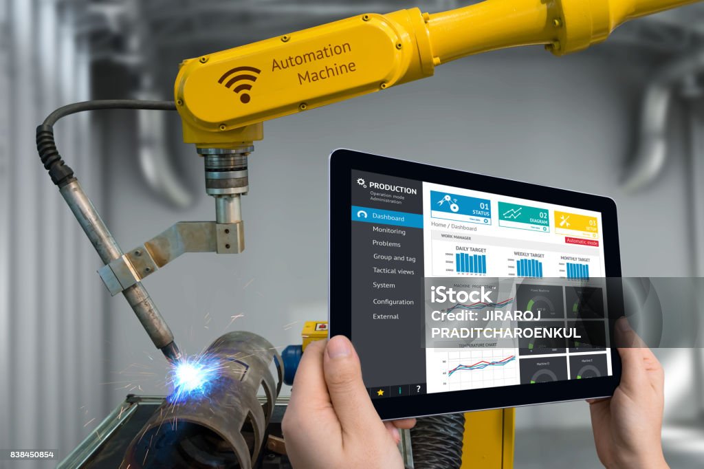 Engineer hand using tablet, heavy automation robot arm machine in smart factory industrial with tablet real time monitoring system application. Industry 4th iot concept. Computer-Aided Manufacturing Stock Photo