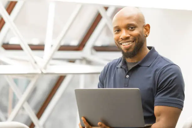 Successful Professional man of African American descendant holding a laptop computer