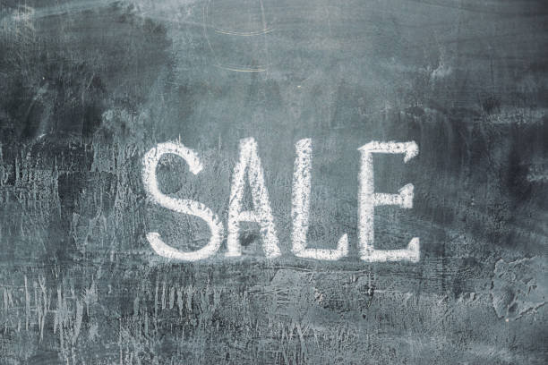 hand drawn lettering of sale in chalk on black slate with copy space for your text