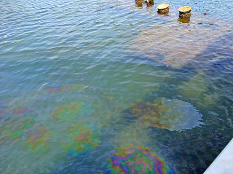 Multi colored oil spots floating on water, sunken ship moorings, USS Arizona Memorial, Hawaii, Oahu