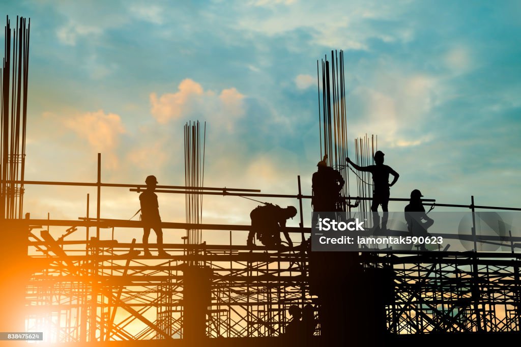 Silhouette de l’équipe d’ingénieur et de la construction travaillent en toute sécurité sur un échafaudage sur immeuble de grande hauteur. au cours de pastel sunset arrière-plan flou pour le fond de l’industrie avec la Foire Light - Photo de Chantier de construction libre de droits