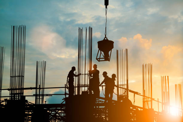 silhouette di ingegnere e team di costruzione che lavorano in sicurezza caricano calcestruzzo su impalcature su grattacieli. su sfondo sfocato tramonto pastello per sfondo del settore con fiera light - equipment planning work tool plan foto e immagini stock