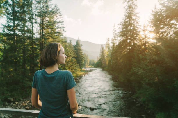 Young Caucasian woman looking at river in mountains