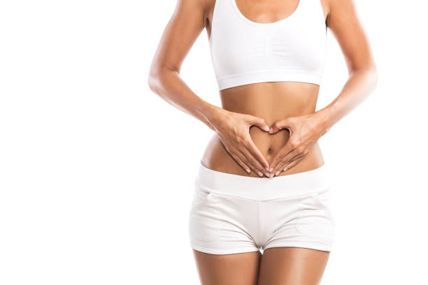 forma joven sosteniendo un corazón sobre su abdomen, aislado sobre fondo blanco - desintoxicación fotografías e imágenes de stock