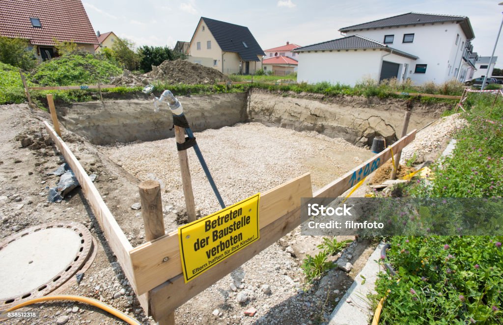 construction pit for foundation of residential house construction pit for foundation of residential house with sign in german language: keep off construction site - Parents are liable for their children Grounds Stock Photo