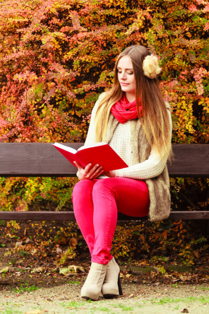 istock Woman relaxing in autumnal park reading book 838518876