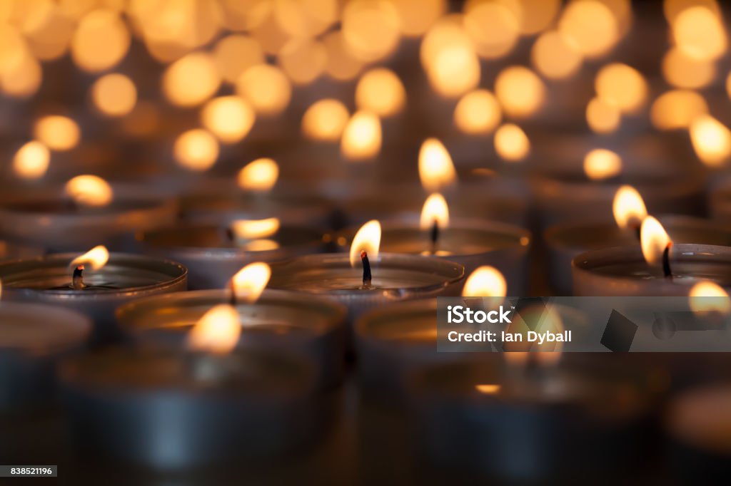 Lighted candle amongst many flaming tea light candles. Beautiful romantic candlelight. Lighted candle amongst hundreds of flaming tea light candles. Beautiful romantic candlelight. Selective focus on central lit wick. Candle Stock Photo