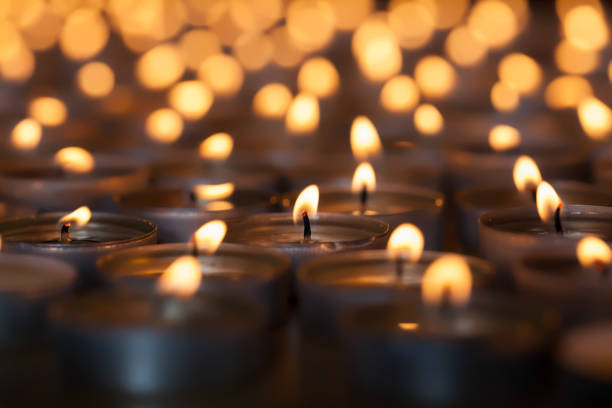 Lighted candle amongst many flaming tea light candles. Beautiful romantic candlelight. Lighted candle amongst hundreds of flaming tea light candles. Beautiful romantic candlelight. Selective focus on central lit wick. ian stock pictures, royalty-free photos & images