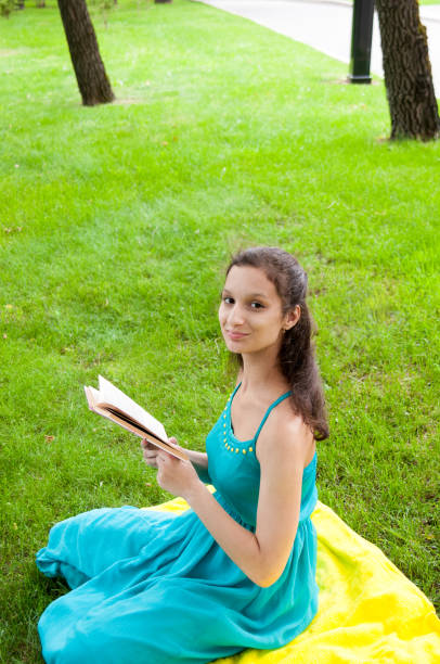 istock Brunette is sitting with a book on the lawn 838525204