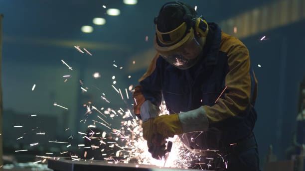 istock Heavy industry worker at a factory is working with metal on a angle grinder while hot sparks are produced in a result. 838527514