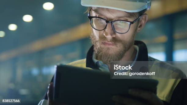 Engineer In Hardhat Is Using A Tablet Computer In A Heavy Industry Factory Stock Photo - Download Image Now