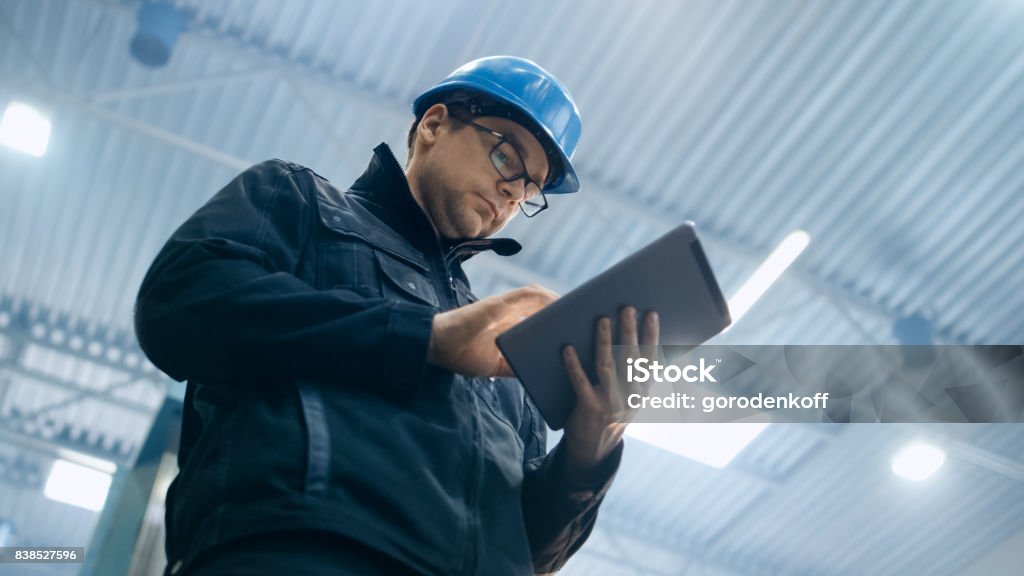 Trabajador de la fábrica en un casco está utilizando un equipo tablet PC. - Foto de stock de Gerente libre de derechos