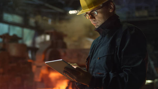 ingeniero en vasos con tablet pc en fundición. entorno industrial. - foundry industry iron melting fotografías e imágenes de stock