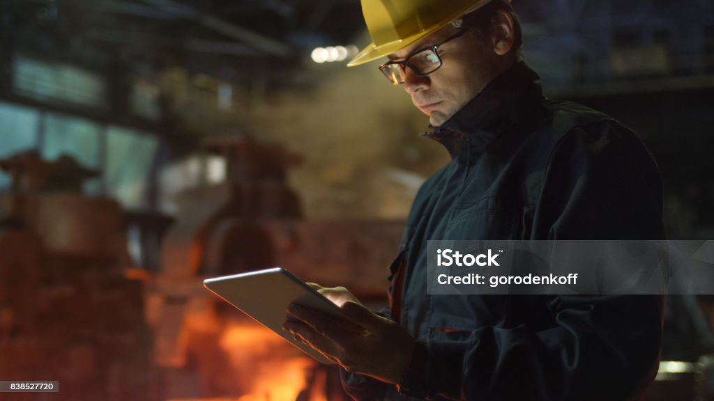 Engineer in Glasses using Tablet PC in Foundry. Industrial Environment. Steel Mill Stock Photo