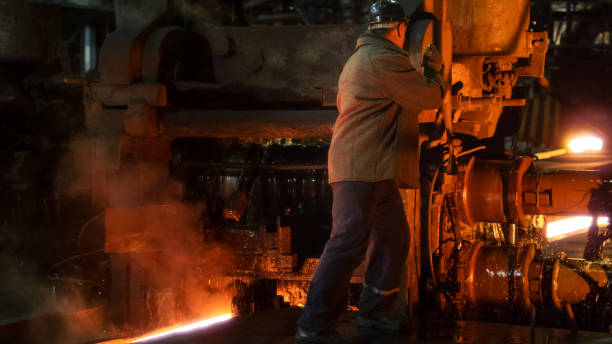 Heavy Industry Worker Working Hard on Machine in Foundry. Rough Industrial Environment. Wide Shot. Heavy Industry Worker Working Hard on Machine in Foundry. Rough Industrial Environment. Wide Shot. Furnace stock pictures, royalty-free photos & images