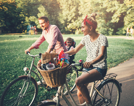 Young family with a child riding bicycles in the park
