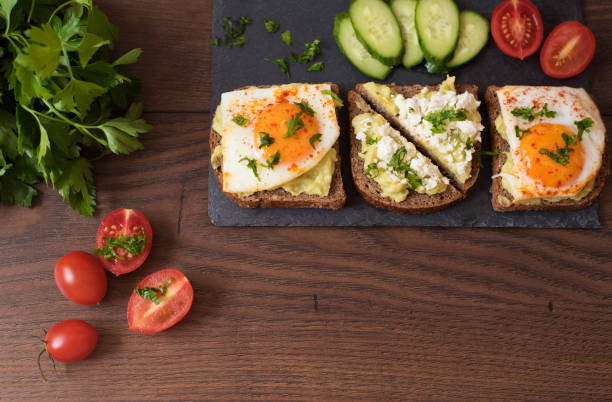 Avocado Toast. Healthy Breakfast. Top View. Homemade Sandwich With Avocado And Fried Eggs, Cherry Tomato And Cucumbers On A Wooden Background. Dark Food Photography Avocado Toast. Healthy Breakfast. Top View. Homemade Sandwich With Avocado And Fried Eggs, Cherry Tomato And Cucumbers On A Wooden Background. Dark Food Photography egg cherry tomato rye stock pictures, royalty-free photos & images