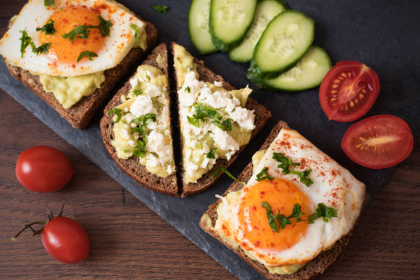 Avocado Toast. Healthy Breakfast. Top View. Homemade Sandwich With Avocado And Fried Eggs, Cherry Tomato And Cucumbers On A Wooden Background. Dark Food Photography Avocado Toast. Healthy Breakfast. Top View. Homemade Sandwich With Avocado And Fried Eggs, Cherry Tomato And Cucumbers On A Wooden Background. Dark Food Photography egg cherry tomato rye stock pictures, royalty-free photos & images