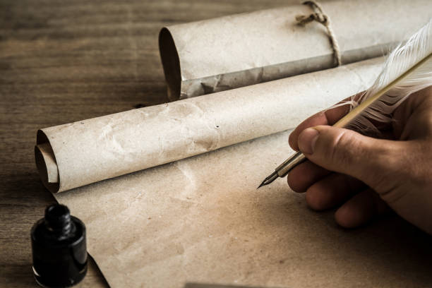 mano escribiendo con pluma antigua en el viejo papel. ambiente histórico. lugar vacío para un texto. - scroll parchment paper old fotografías e imágenes de stock