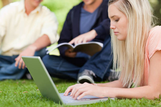 istock Close up of a girl using a netbook while lying in a park 838557492