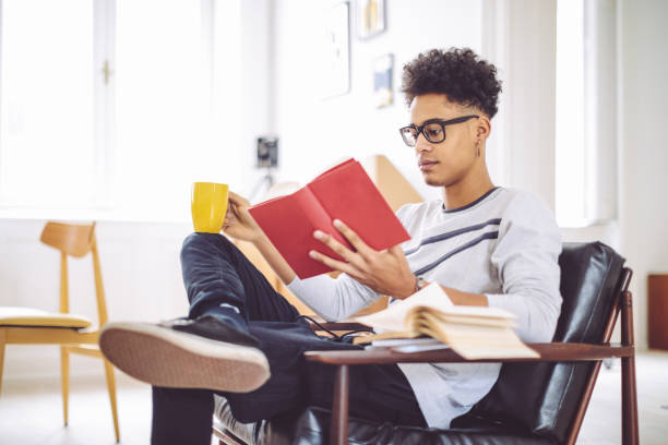 istock Young man reading a book at home 838563286