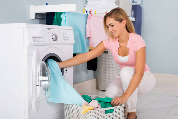 istock Smiling Woman Putting Clothes In Washing Machine 838575536