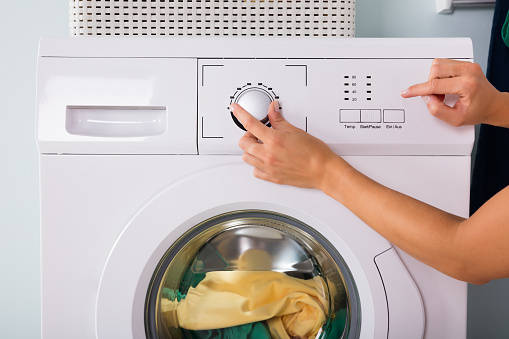 Close-up Of Person Hand Pressing Button Of Washing Machine For Laundry