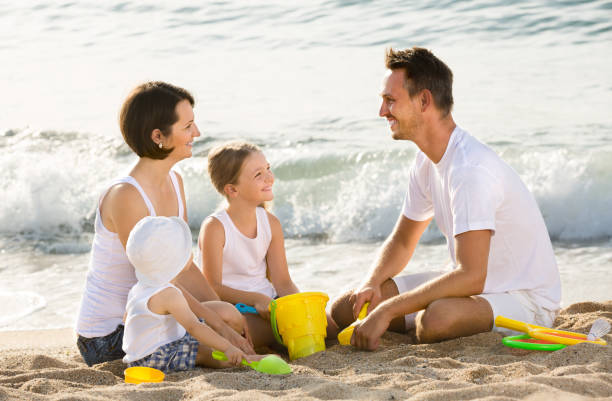 istock Happy family with two children playing at beach 838669508
