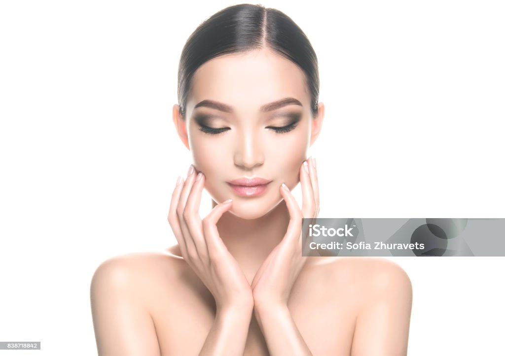 Gorgeous, young asian woman with clean, fresh skin is touching own face. Cosmetology. Gorgeous, young, asian black haired woman with clean fresh skin is touching the face. Asian beauty. Facial treatment, cosmetology, beauty technologies and spa. Asia Stock Photo