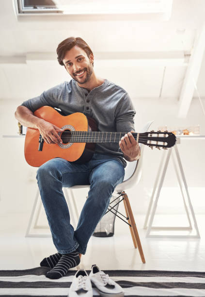 istock Shot of a handsome young man practising guitar at home 838721024